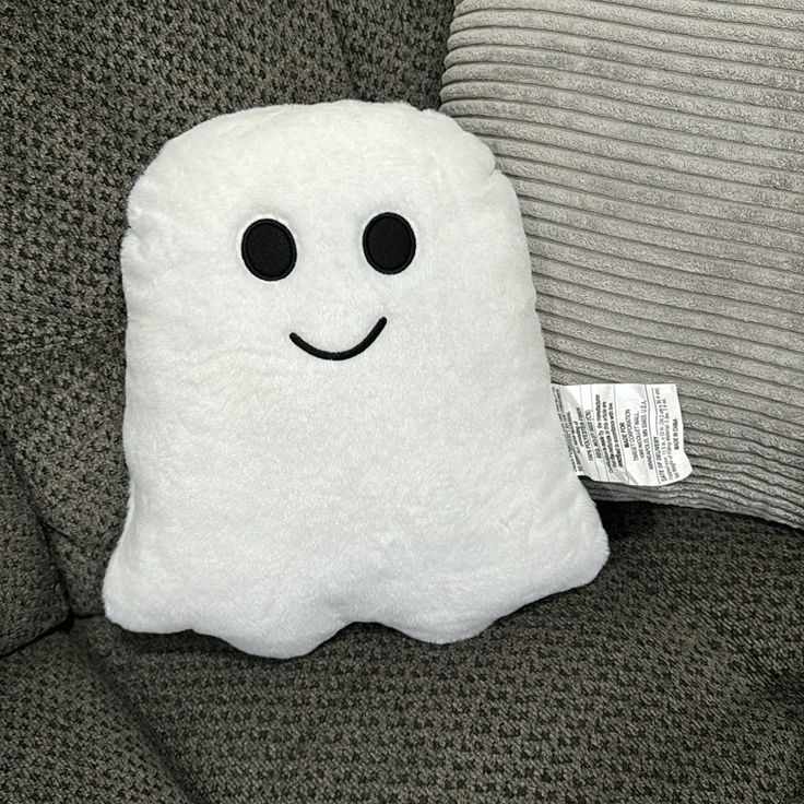 a stuffed ghost pillow sitting on top of a couch