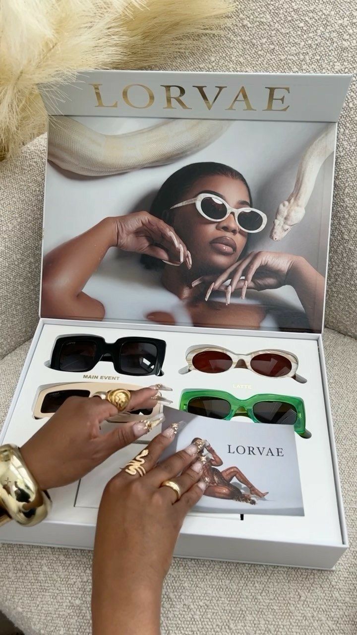 a woman sitting on a couch with her hands in front of the box that contains sunglasses