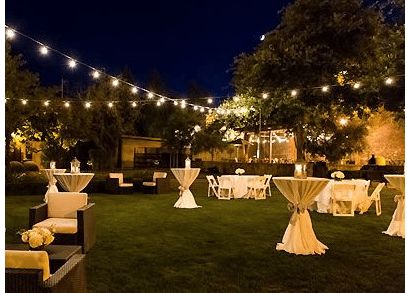 tables and chairs are set up in the yard for an outdoor dinner party at night