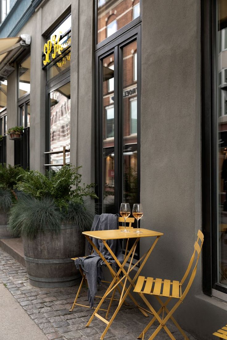 two yellow chairs and a table on the side of a building