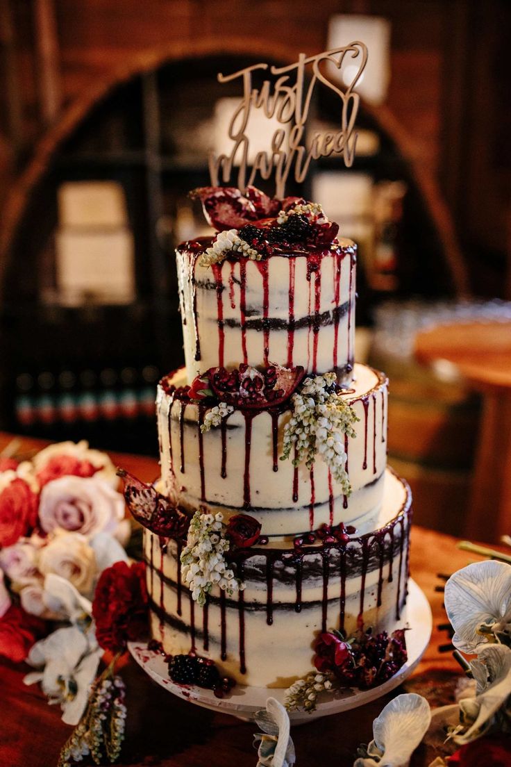 a three tiered wedding cake with red and white icing on top, sitting on a table