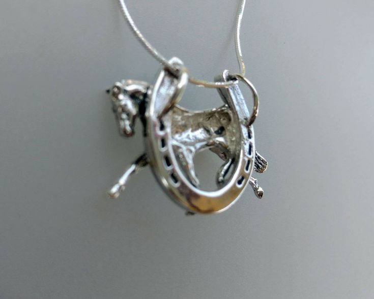 a silver necklace with a horse on it's back and an arrow in the middle