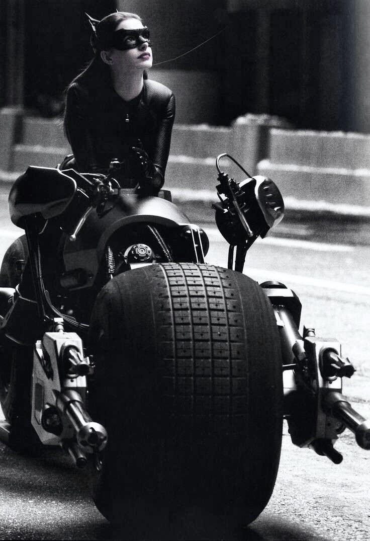 a woman riding on the back of a motorcycle with a catwoman costume and helmet