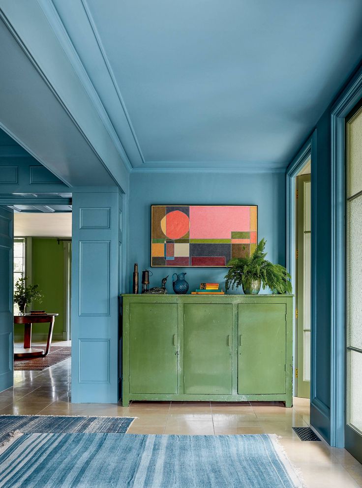 a living room with blue walls and green furniture in the center, along with an area rug on the floor