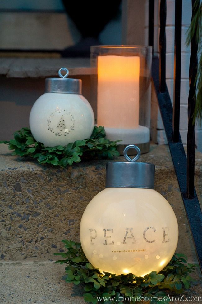 two white vases sitting on the ground next to each other with candles in them