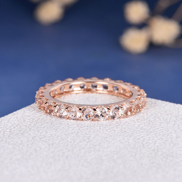 a rose gold wedding band with round cut diamonds on the inside and outside, sitting on top of a white surface