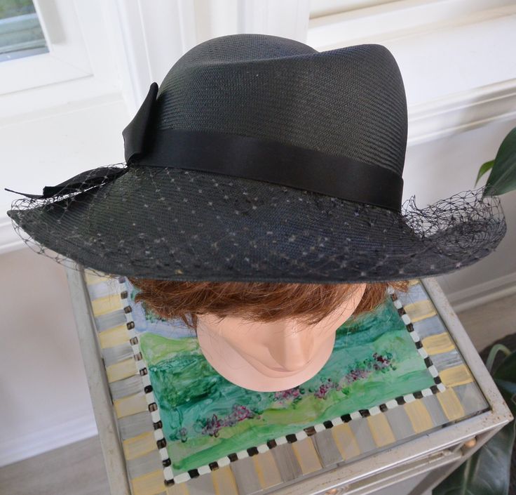 A fabulous vintage Neiman Marcus millinery black dress hat. This elegant hat features millinery fabric, an elegant large bow, and black netting. It carries a "Neiman Marcus" fabric tag. This striking hat is a multi occasion/season hat: perfect for church, weddings, tea party, concerts, horse racing, etc. In great condition.  Perfect for lovers of exquisite classic vintage top department store vintage dress hats. Wonderful addition of a rare retro millinery Neiman Marcus stunning great shape black hat with netting and a lovely bow for your wardrobe or give it as a special gift - please see photos. (Enjoy complimentary US shipping and lower shipping elsewhere). Measures about: circumference 22 inches, height 3 inches,  brim 2 - 3 inches (depending on where you measure).   Enjoy! * There are Vintage Black Adjustable Sun Hat, Vintage Black Straw Hat With Curved Brim, Vintage Black Straw Hat With Short Brim, Vintage Black Brimmed Straw Hat, Vintage Black Brimmed Sun Hat, Vintage Black Adjustable Boater Hat, Vintage Adjustable Black Boater Hat, Black Vintage Sun Hat For Beach, Black Wide Brim Fedora For Evening