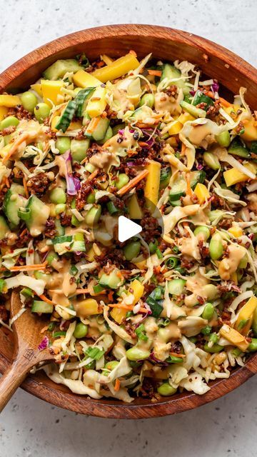 a wooden bowl filled with coleslaw and vegetables