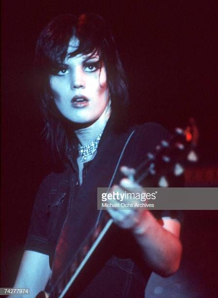 a woman with black hair and piercings holding a guitar in her right hand, with an quote from joan jettt on it