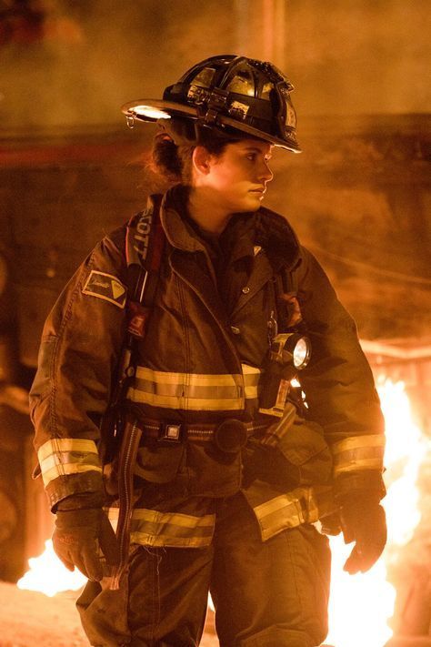 a firefighter standing in front of a large fire with flames coming out of it