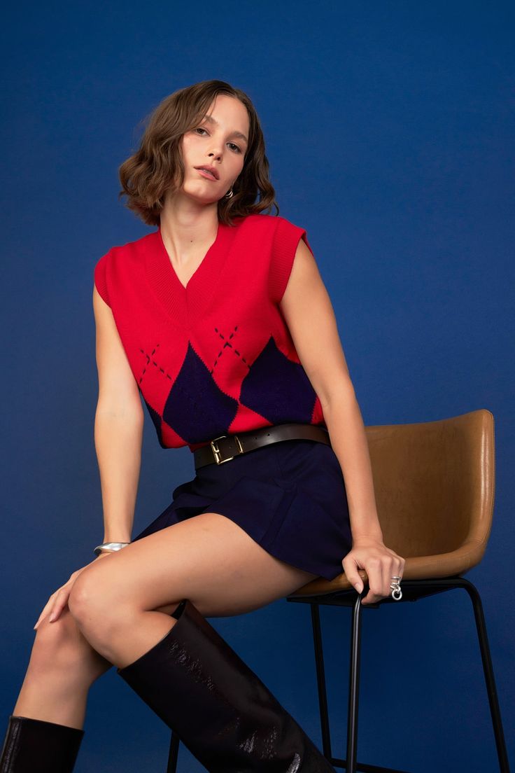 a woman sitting on top of a chair wearing knee high boots and a red sweater