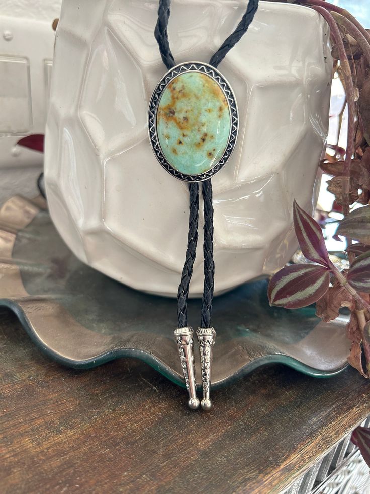 "This awesome bolo tie has a southwestern design and turquoise colored agate centerpiece. All stones are different. The cord is genuine black leather and it has silber metal detailing. Our bolos pair nicely with many of our belt buckles! They make wonderful gifts.    The western bolo tie rope length is 100cm(39\") ; charm agate stone pendant size is 5*4cm(1.97*1.57in)" Handmade Artisan Bolo Ties For Western-themed Events, Western Jewelry With Adjustable Length For Rodeo, Western Jewelry With Adjustable Length For Western-themed Events, Western Style Lariat Jewelry For Gifts, Western Style Adjustable Jewelry For Western-themed Events, Western Lariat Jewelry As Gift, Western Style Lariat Jewelry As Gift, Handmade Adjustable Western Bolo Ties, Southwestern Adjustable Bolo Tie With Sliding Knot