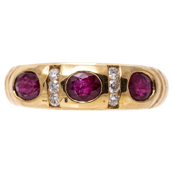 14k yellow gold ring. This contemporary yellow gold band ring is set with three horizontal set, faceted oval, dark pinkish red color rubies, approximately 0.57 TCW, flush set and alternating with two vertical set channels of round faceted diamonds, approximately 0.06 TCW. Marks: 14k Dimensions: 5/8" across the top x 7/32" wide Weight: 2.1 gross dwt Ring Size: 6.25 Diamond Band Ring, Pinkish Red, Rings Engagement, Gold Band Ring, Diamonds And Gold, Diamond Rings Bands, Yellow Gold Ring, Diamond Band, Ruby Ring