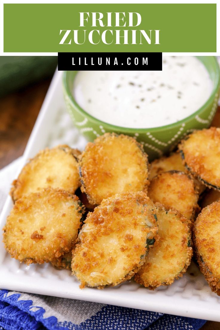 fried zucchini on a white plate with ranch dressing in the background and text overlay that reads fried zucchini