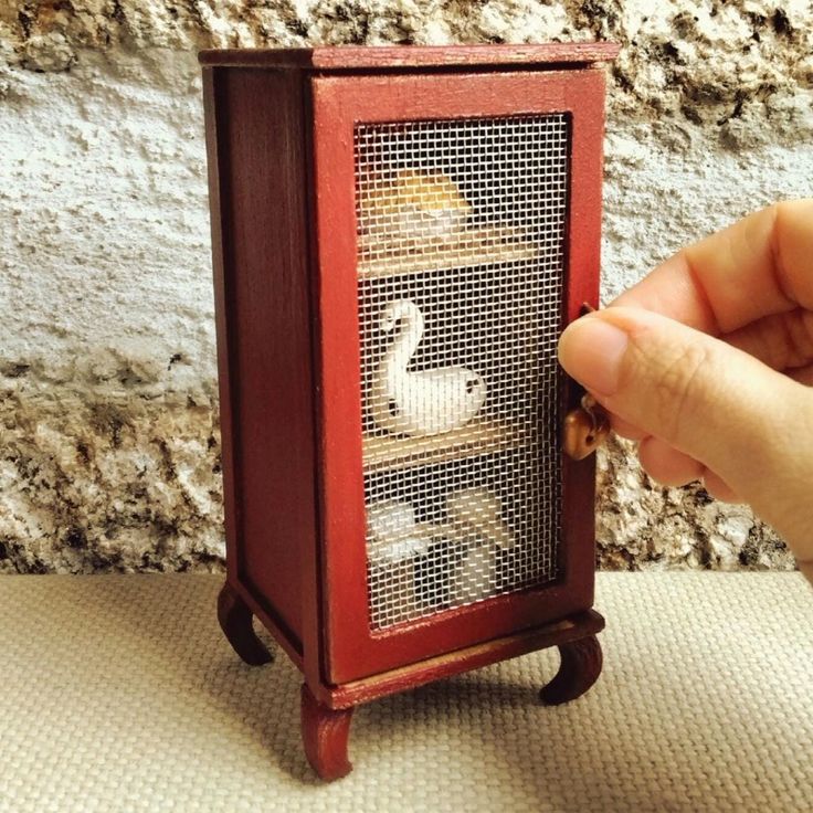 a person is holding a miniature bird cage