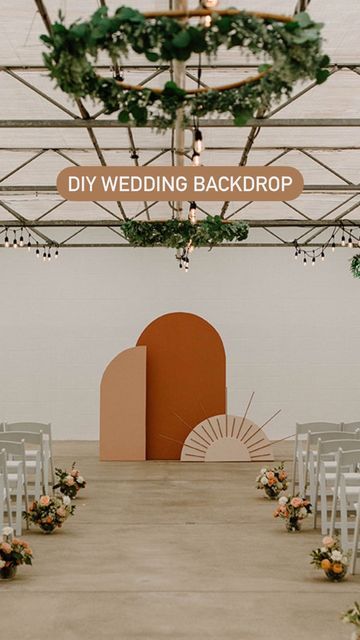 an indoor wedding setup with white chairs and greenery