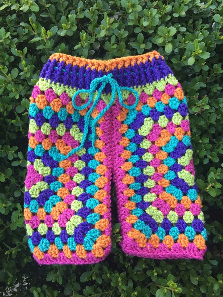 a colorful crocheted shorts hanging from a tree