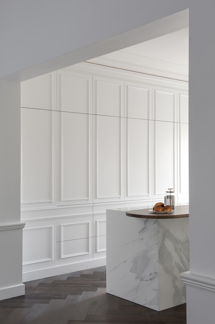 an empty room with white walls and marble counter top in the center, along with hardwood flooring