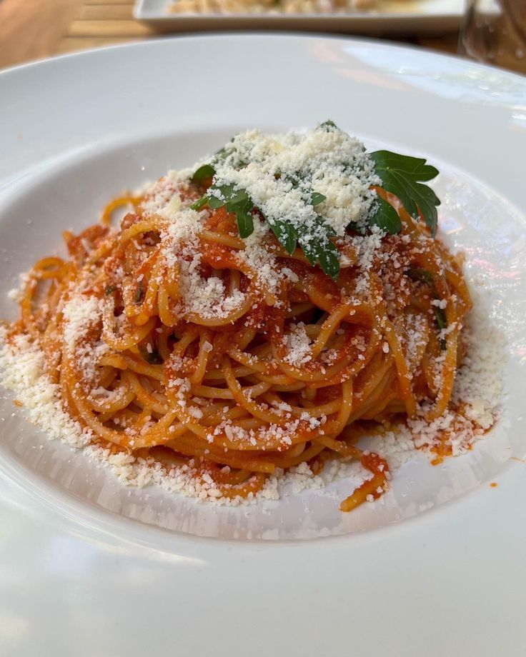 a white plate topped with spaghetti and parmesan cheese