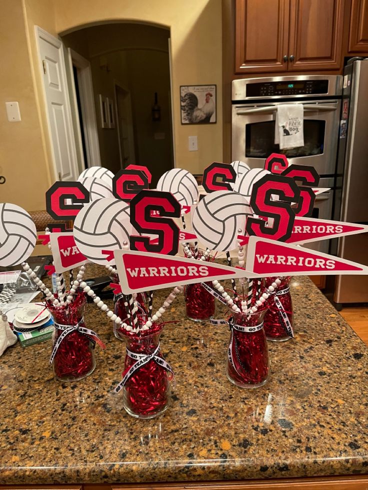 four red vases filled with candy sitting on top of a kitchen counter next to an oven