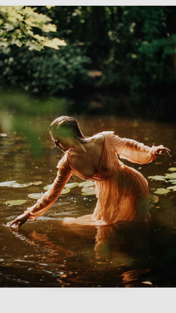 a woman standing in the water with her arms outstretched