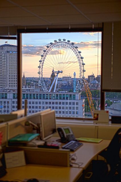 an office with a view of the london eye in the distance, looking out over the city