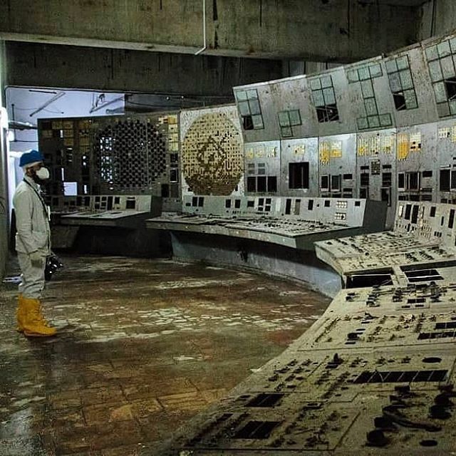 a man standing in front of an old control room filled with lots of buttons and screens