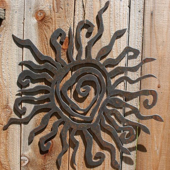 a metal sun on the side of a wooden fence