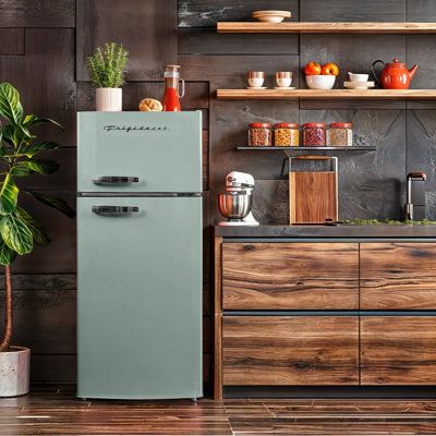 an old fashioned refrigerator in a kitchen next to a wooden cabinet and potted plant