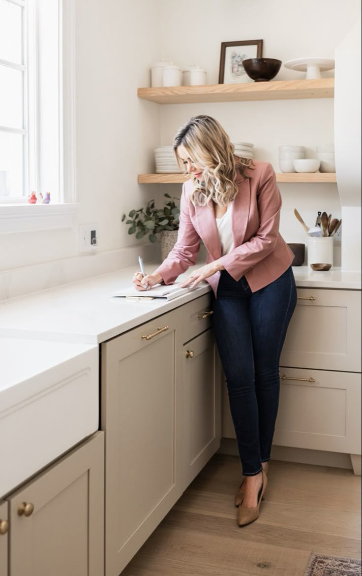 a woman is sitting on the kitchen counter writing