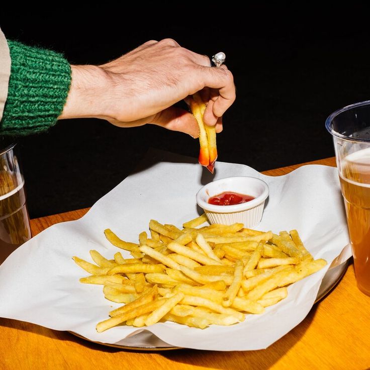 a person is eating french fries with ketchup on the side at a restaurant