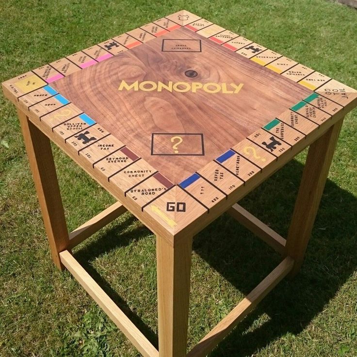 a wooden board game table sitting on top of a grass covered field with the word monopoly written on it