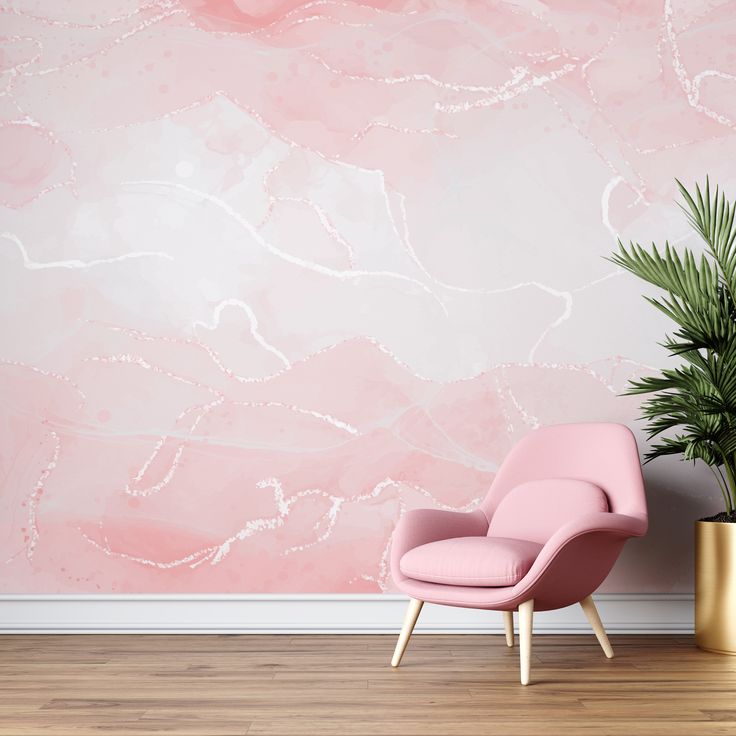 a pink chair sitting next to a plant in front of a wall with a painting on it