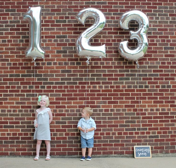 two young children standing in front of a brick wall with the number twenty thirteen on it