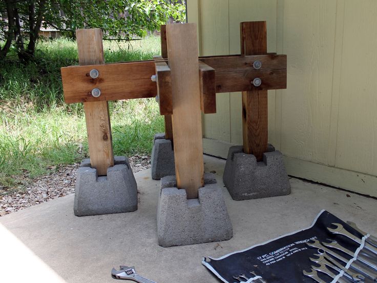 three wooden crosses sitting on top of cement blocks next to a wrench and pliers