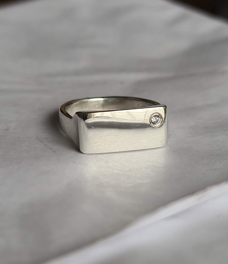 "Eleve su juego de meñique con nuestro exquisito anillo de plata rectangular. Este exclusivo anillo para el dedo meñique cuenta con un diseño contemporáneo que combina sin esfuerzo el minimalismo con un toque de lujo. El punto focal es una cautivadora zirconia, delicadamente colocada en la esquina, agregando un brillo sutil que llama la atención. Ya sea como una pieza independiente o como parte de su pila de anillos favorita, este accesorio es un testimonio de su refinado gusto e individualidad. Adopte la elegancia discreta con nuestro anillo plateado para el dedo meñique, un complemento imprescindible para su colección de joyas\"." Formal Sterling Silver Signet Ring With Rectangular Stone, Modern White Gold Rings With Rectangular Stone, Modern White Gold Ring With Rectangular Stone, Modern Silver Rings With Rectangular Stone, Modern Silver Ring With Rectangular Stone, Fine Jewelry Silver Signet Ring With Diamond, Silver Fine Jewelry Signet Ring With Diamond, Sterling Silver Rings With Rectangular Stone For Formal Events, Sterling Silver Rings With Rectangular Stone For Formal Occasions