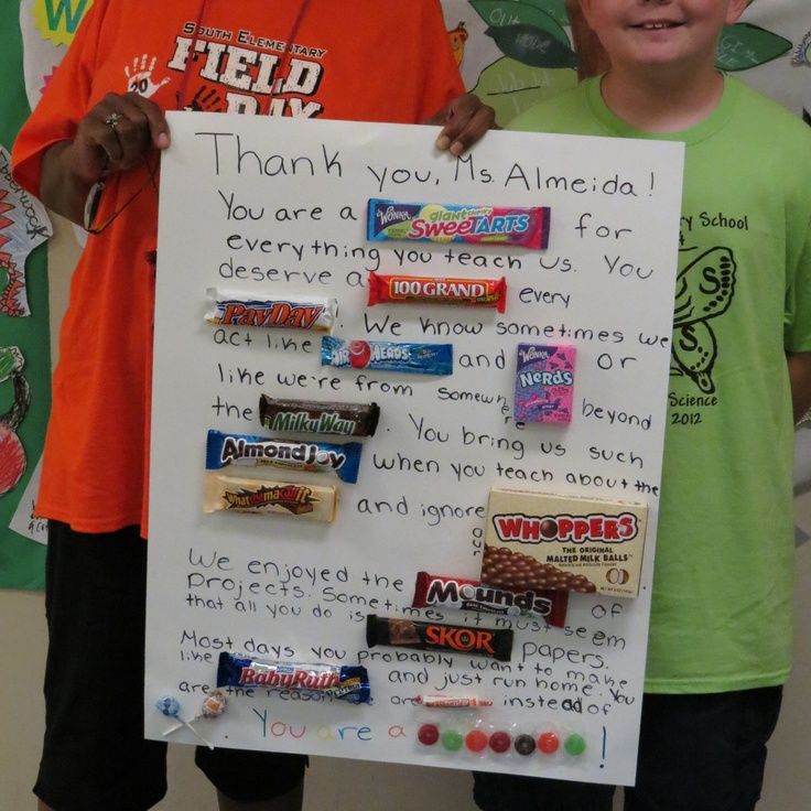 two boys holding up a sign with candy on it