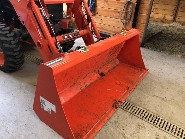 an orange snow plow sitting on top of a garage floor