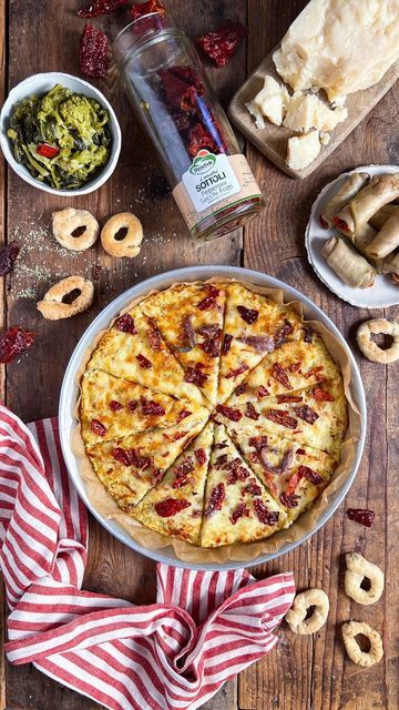 a pizza sitting on top of a wooden table next to other foods and condiments