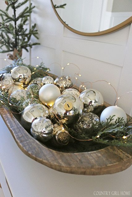 a wooden shelf filled with ornaments on top of a counter next to a mirror and christmas tree