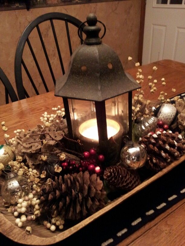 a table with a lantern and pine cones on it