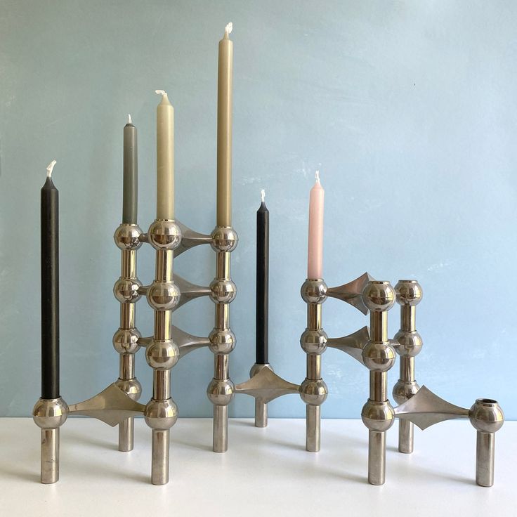 four candles are lined up next to each other on a white counter top with blue walls in the background