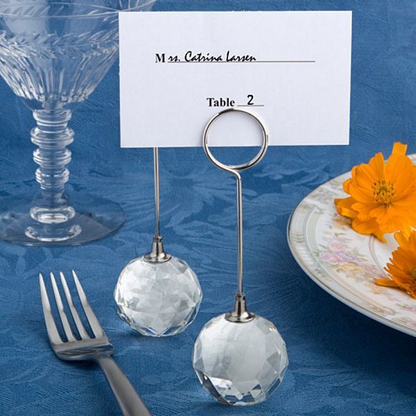 there is a place card holder and silverware on the table with an orange flower