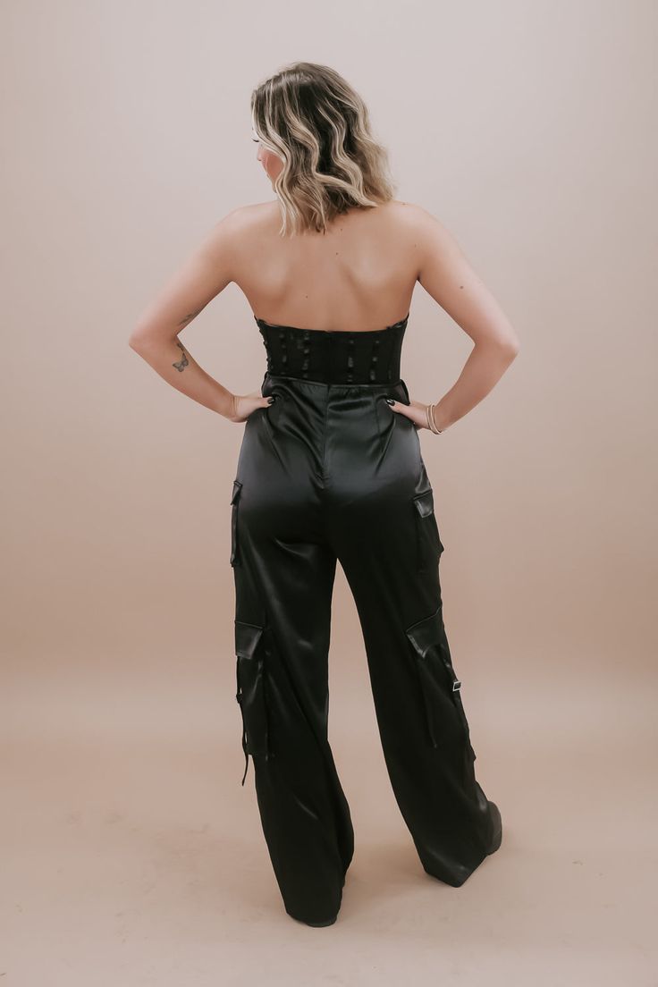 Dress to impress in our Corset Jumpsuit in classic Black. This sleek and stylish one-piece effortlessly combines the edginess of a corset with the ease of a jumpsuit. The black color adds a touch of sophistication, making it a versatile choice for a night out or any special occasion. With its figure-flattering silhouette and fashion-forward design, our Corset Jumpsuit is a must-have in your wardrobe. Zipper closure in the back strap-less Corset top Mesh material on the upper half of the jumpsuit Fitted Strapless Jumpsuit For Night Out, Strapless Fitted Jumpsuit For Night Out, Backless Jumpsuits With Built-in Bra For Night Out, Chic Fitted Strapless Bodysuit, Chic Strapless Fitted Bodysuit, Fitted Satin Bottoms For Night Out, High Waist Corset For Night Out, Chic Evening Corset With Lined Body, Solid Strapless Fitted Jumpsuit For Date Night