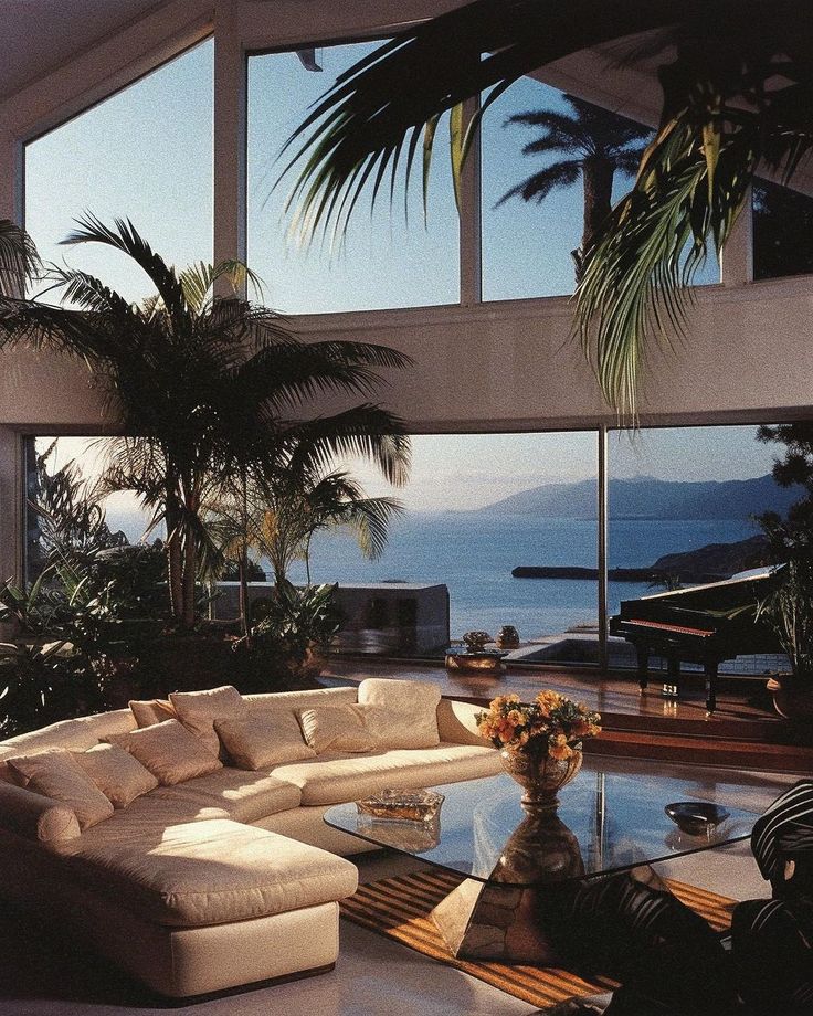 a living room filled with lots of furniture and large windows overlooking the ocean in front of it