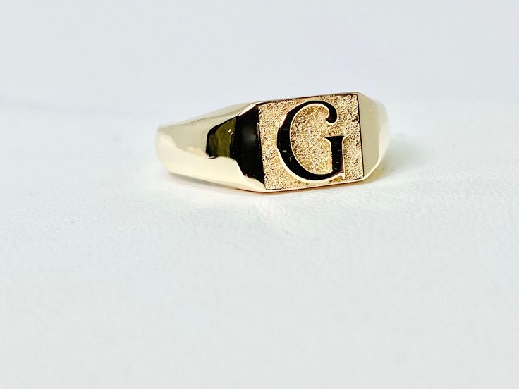 a gold ring with the letter g on it