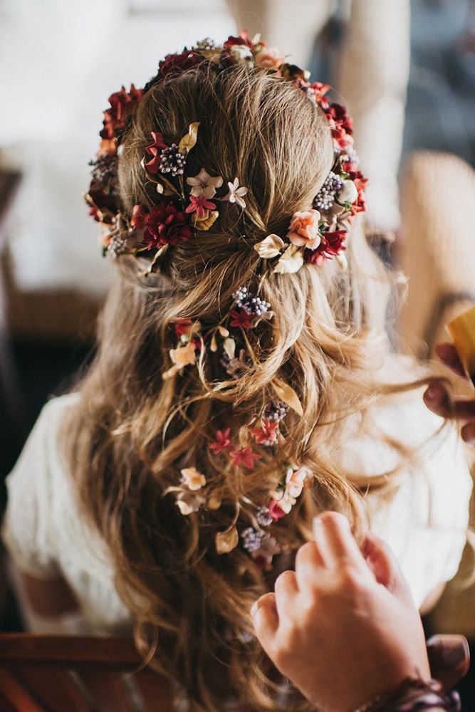 a woman is getting her hair done with flowers in her hair and an orange bottle next to her