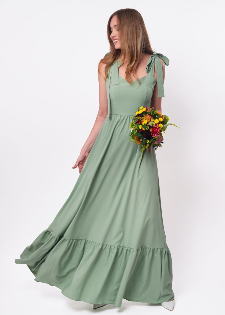 a woman in a long green dress holding flowers