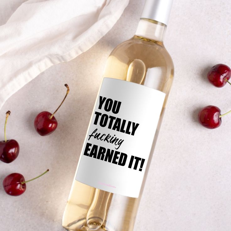 a bottle of wine sitting on top of a table next to some cherries and a napkin