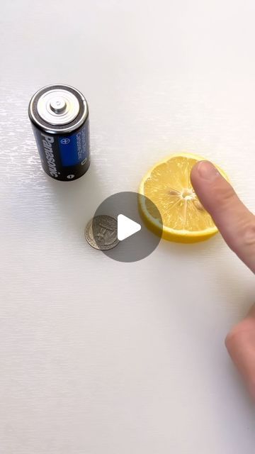 a hand is pointing at a can of soda and a slice of lemon on the table